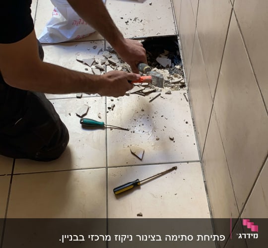 אדם חופר ברצפה עם כלים לגילוי נזילות